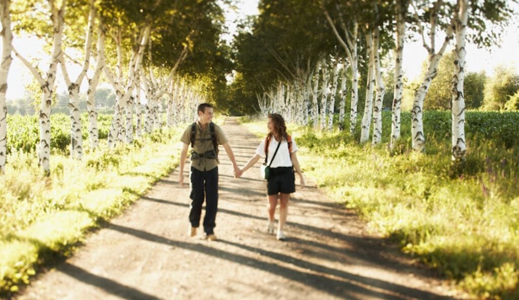 couple walking down path while holding hands