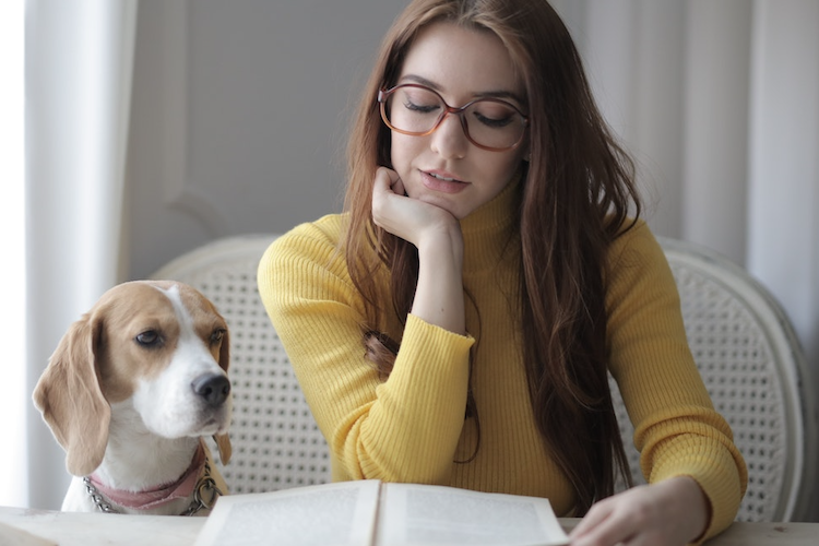 Young woman reading book with her dog