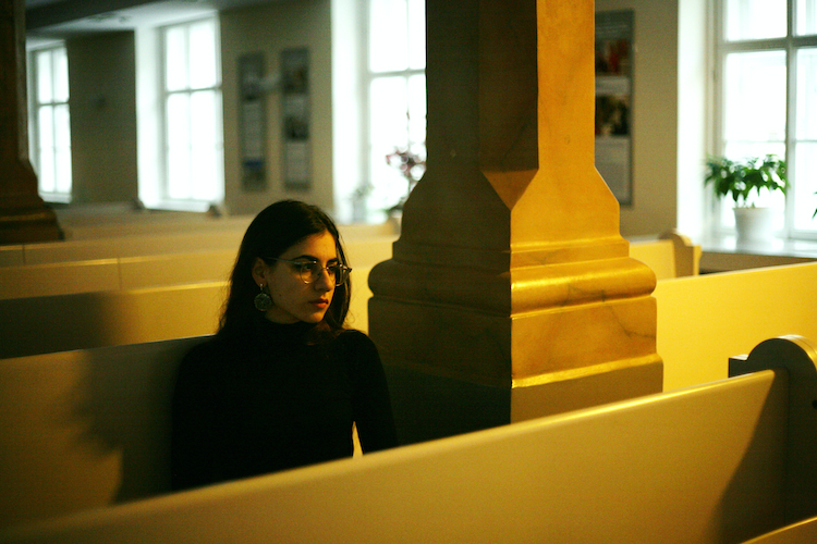 Young woman sitting at pews inside a church