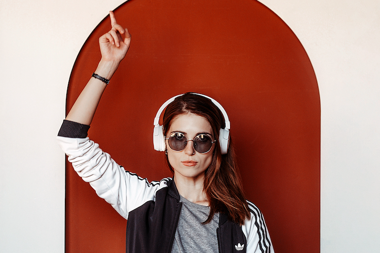 young woman listening to music while pointing up