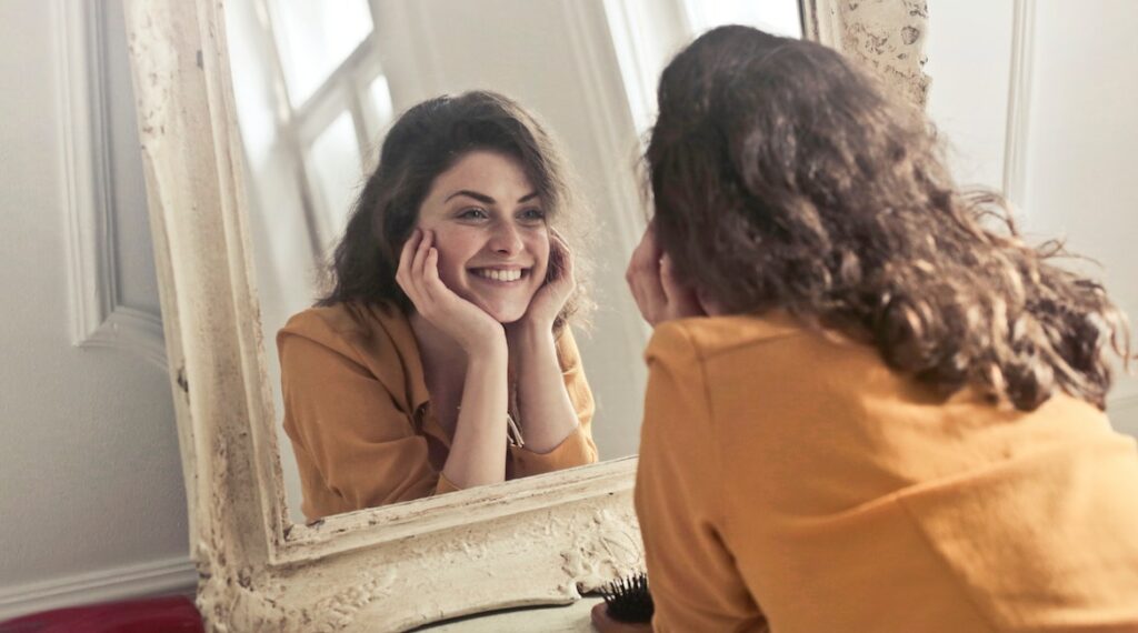 young woman looking at reflection in the mirror