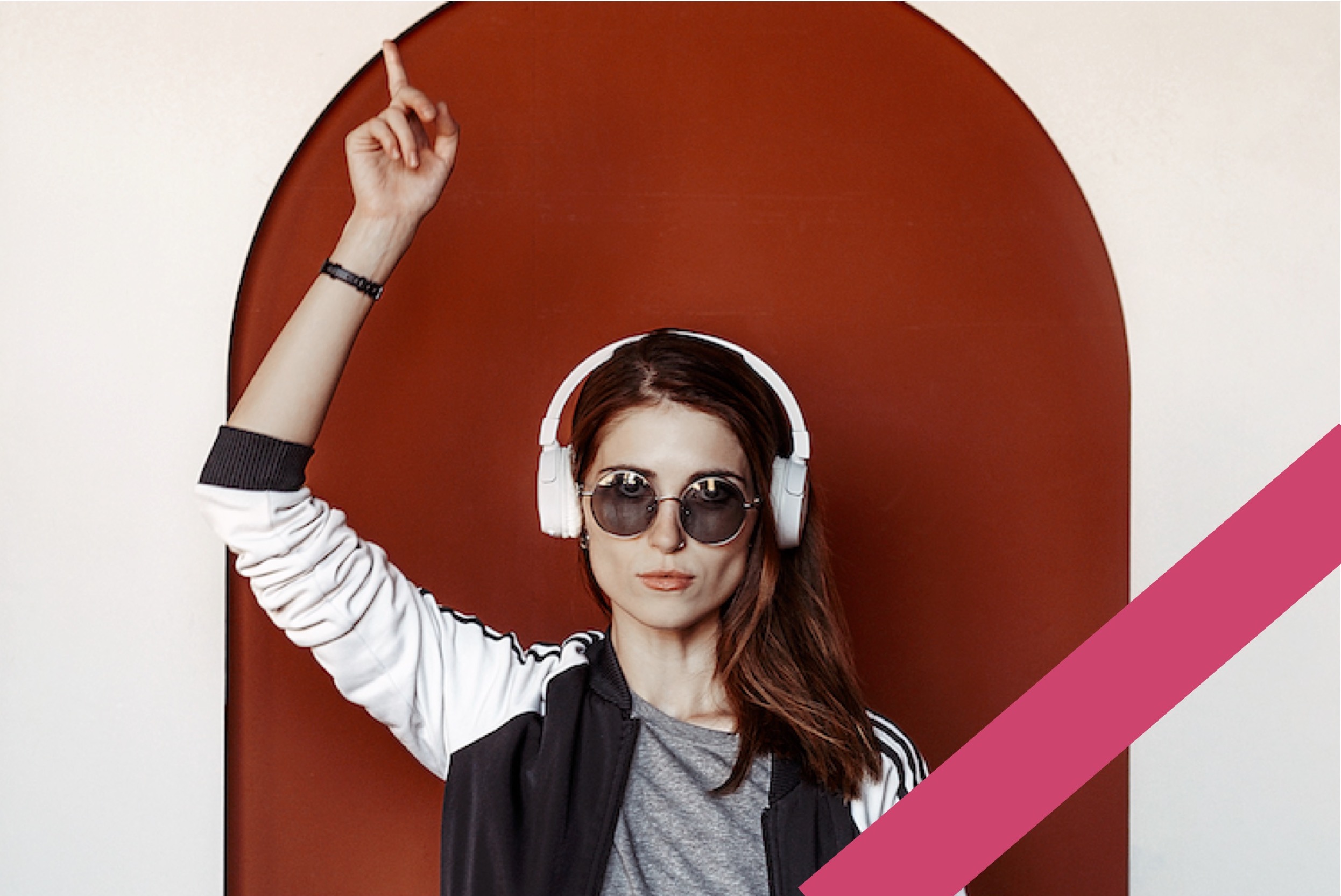 beautiful woman wearing cool sunglasses pointing upward with earphones on